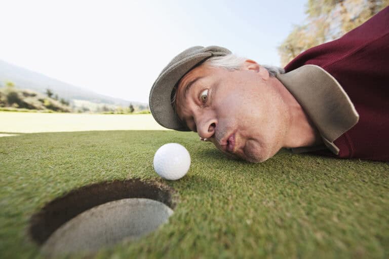 Man Blowing a Golf Ball into the Hole